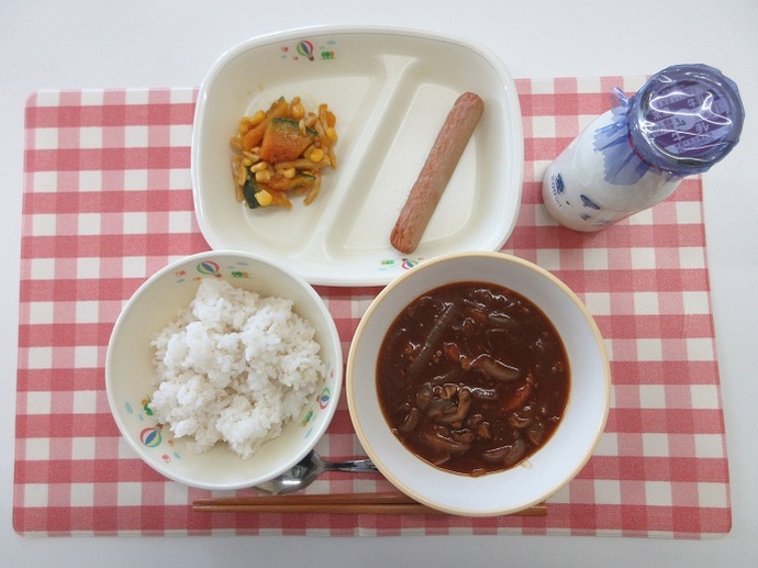 献立：麦ごはん　牛乳　ハヤシライス　焼きソーセージ　かぼちゃとハムのサラダ
